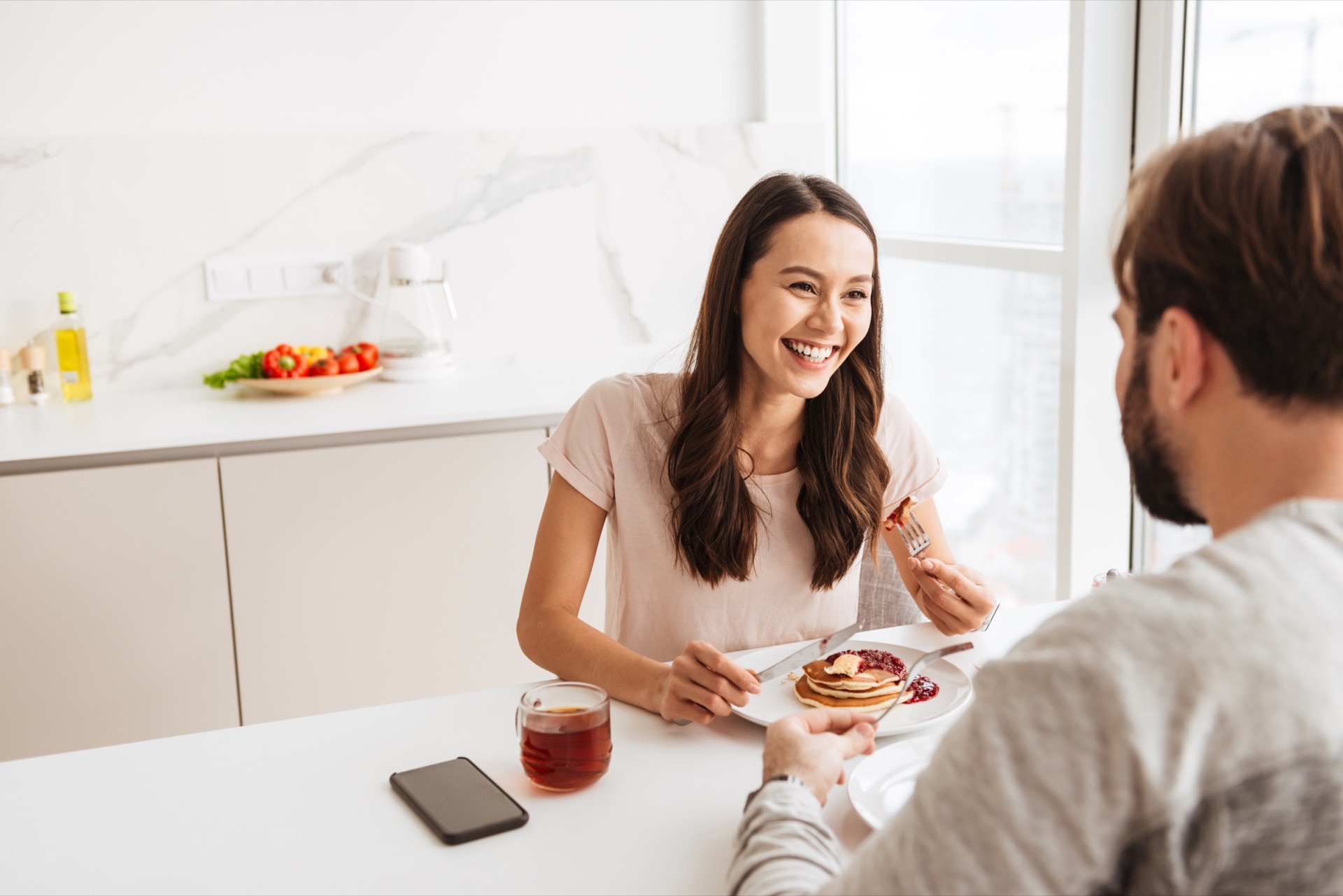Laughing young couple having breakfast while sitting together at the table on a kitchen