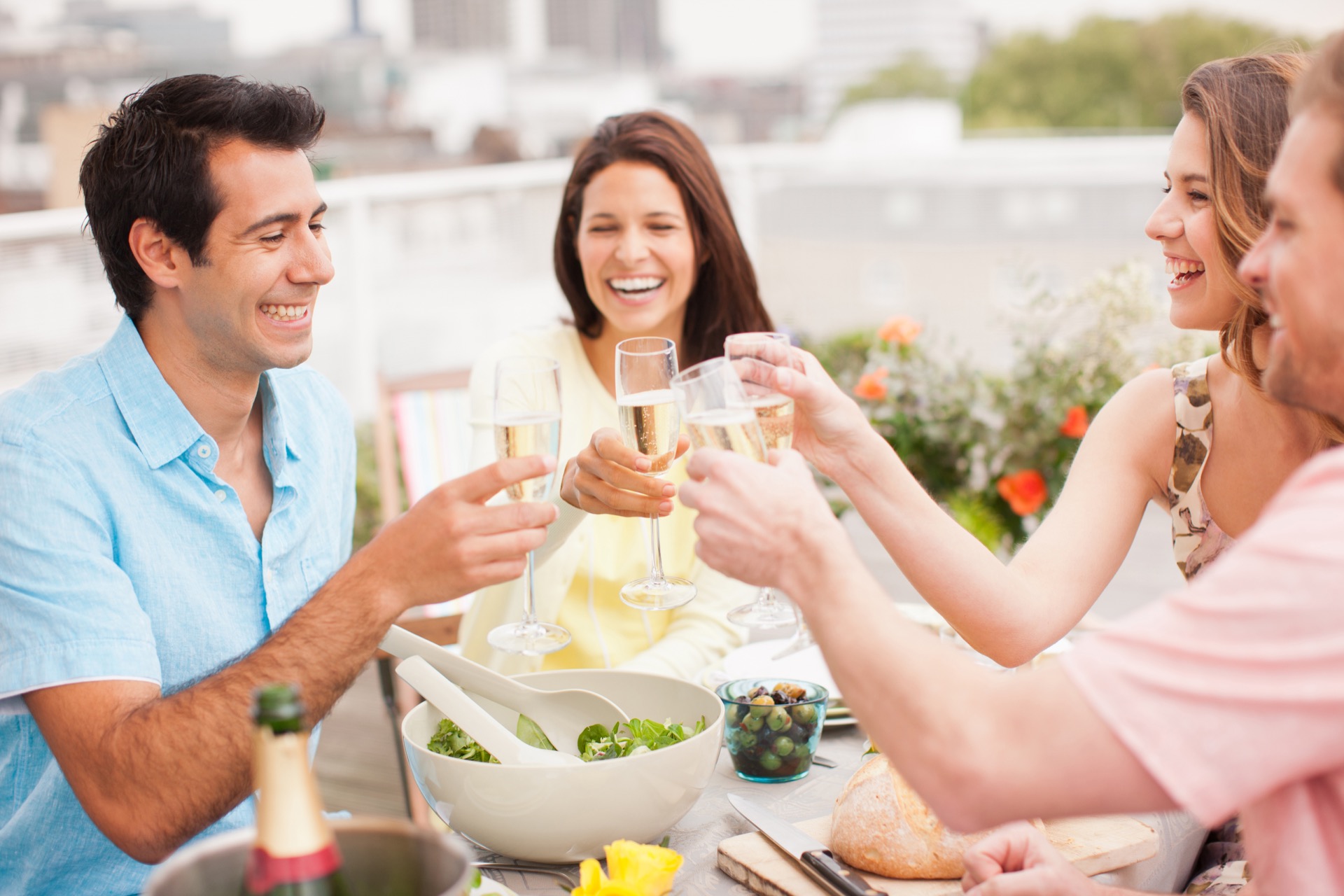 Laughing couples toasting with Champagne outdoors at their downtown Baltimore apartments