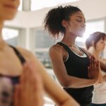 Fit young woman practice yoga with friends. Fitness female doing yoga meditation indoors in the gym at Cirro apartments in downtown Baltimore